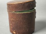 an old brown box with a green lid sitting on top of a table