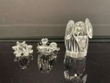 figurines en cristal représentant des anges et des fleurs, posées sur une table noire