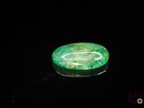 a close up of a green stone on a black surface