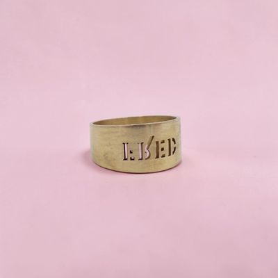 un gros plan d'une bague en or sur fond rose