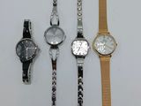 four different watches are lined up on a white surface