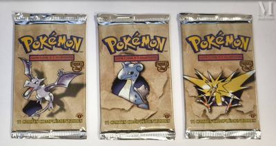 three packs of pokemon trading cards sitting on top of a table