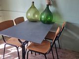 a table and chairs in a room with a vase on the table