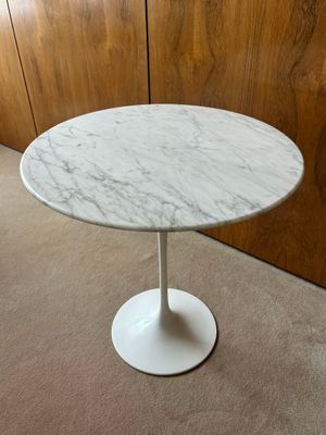 une photo d'une table en marbre blanc dans une pièce aux murs lambrissés
