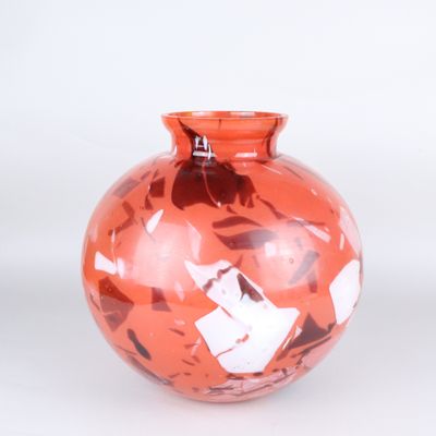 a red vase that has a lot of small pieces of paper on it