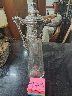 une cafetière en argent posée sur une table, sur laquelle est posée une note