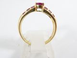 a close up of a gold ring with a ruby stone