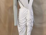 a white dress on a mannequin mannequin stand against a beige backdrop