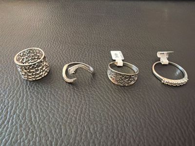 three silver rings on a black leather surface with a price tag