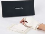 someone is holding a pair of white gloves with a box in the background