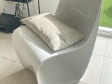 une chaise blanche avec un coussin dessus, dans un salon