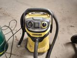 un aspirateur jaune et noir posé par terre à côté d'une poubelle verte
