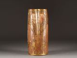 a brown vase with gold designs on it on a gray surface