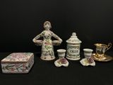 une figurine représentant une femme debout à côté d'une boîte et de tasses