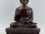 bronze statue of a seated buddha on a pedestal with a white background