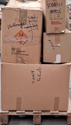 une pile de cartons posée sur une palette dans la rue