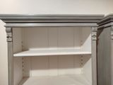 a white cupboard with shelves in the corner of the room