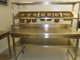 une grande table en inox sur laquelle sont posés des plateaux de nourriture