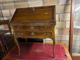 a small wooden desk with a red rug on the floor