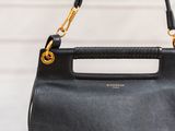 a woman holding a black handbag with a gold handle