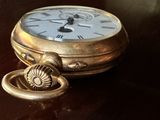une montre de poche en or posée sur une table, avec une clé