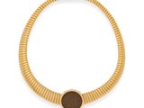 un gros plan sur un collier en or orné d'une pierre marron
