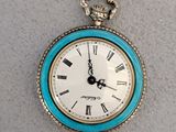 une montre de poche bleue et blanche ornée de chiffres romains