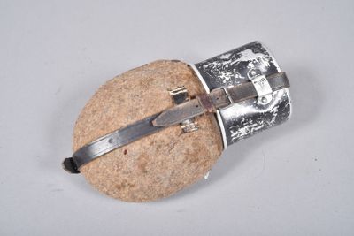 un petit objet en argent posé sur un rocher, dans lequel est enfoncé un couteau