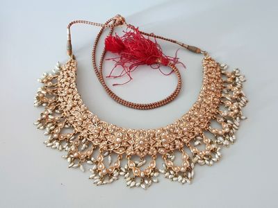 un gros plan sur un collier en or orné d'un pompon rouge