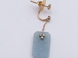 pair of earrings with a blue stone and a gold chain on a white background