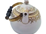 a white tea pot with a gold decoration on it