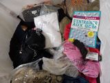 a pile of clothing and a book on a bed
