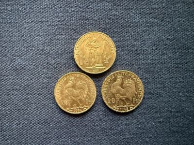 three gold coins sitting next to each other on a blue surface