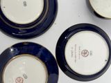 three blue and white plates with gold rims on a white surface