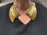 a woman that is wearing a gold necklace with wings on it