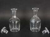 two clear glass bottles sitting next to each other on a black surface