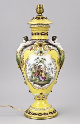 a yellow vase with a painting on it and a light on it
