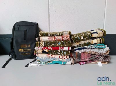 de nombreux morceaux de tissu posés sur une table, à côté d'un sac noir