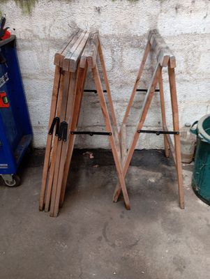 plusieurs morceaux de bois appuyés contre un mur, à côté d'une poubelle