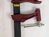 a close up of a clamp on a white surface with a red handle