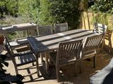 a wooden table and chairs on a patio in the sun