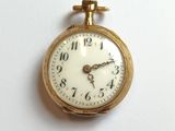 a close up of a gold pocket watch on a white surface