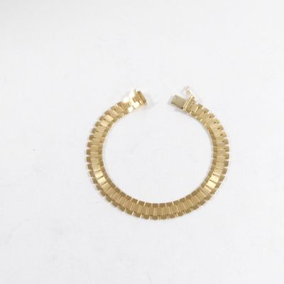 gros plan d'un bracelet en or sur une surface blanche