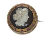 une broche dorée et noire représentant la tête d'une femme