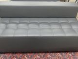 grey leather sofa with foot rest on a rug in a store