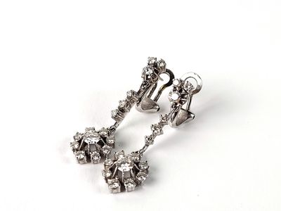une paire de boucles d'oreilles en diamant posées sur une surface blanche, sur fond blanc