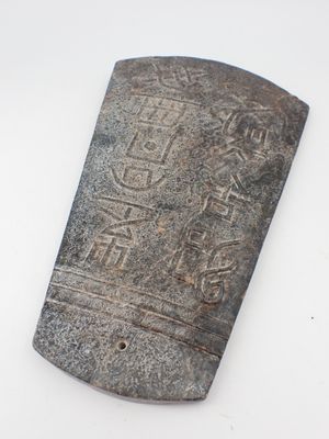 un vieil objet en pierre portant une inscription, posé sur une surface blanche