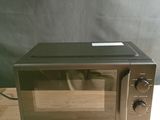 un four à micro-ondes posé sur une table en bois, sur fond noir