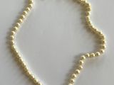 un collier de perles blanches posé sur une surface blanche