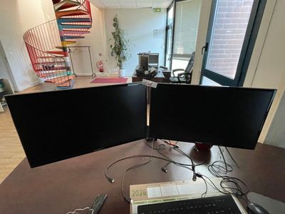 two computer monitors sitting on a desk with a keyboard and mouse